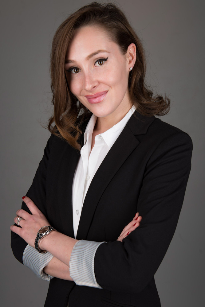 Corporate headshot of a woman in a black blazer with arms crossed