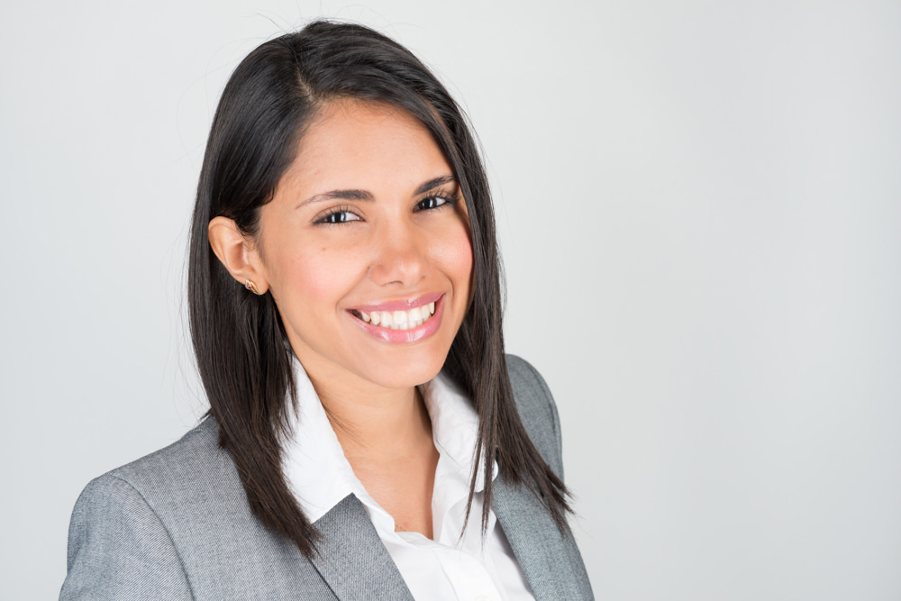 Corporate headshot of a woman in a gray blazer against a neutral gray background