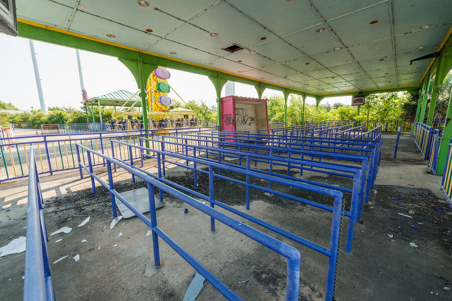 Large format fine art print of the derelict Six Flags New Orleans park at golden hour, rust and vegetation creating an atmosphere of quiet desolation