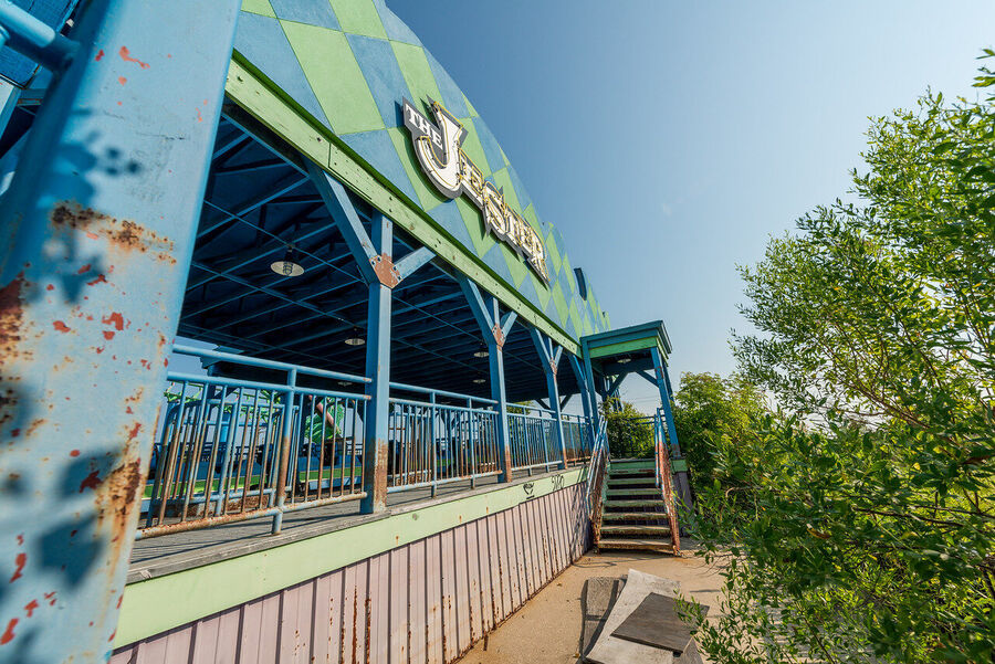 Large format fine art print of the derelict Six Flags New Orleans park at golden hour, rust and vegetation creating an atmosphere of quiet desolation