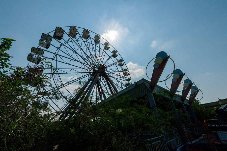 Large format fine art print of the derelict Six Flags New Orleans park at golden hour, rust and vegetation creating an atmosphere of quiet desolation