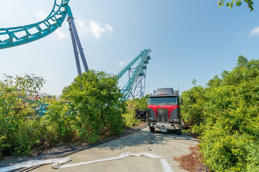 Atmospheric fine art photograph of abandoned roller coaster tracks rising above an overgrown New Orleans landscape, dramatic sky overhead