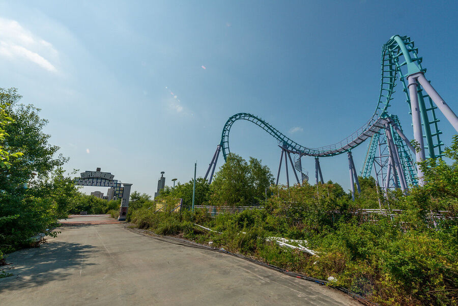Large format fine art print of the derelict Six Flags New Orleans park at golden hour, rust and vegetation creating an atmosphere of quiet desolation