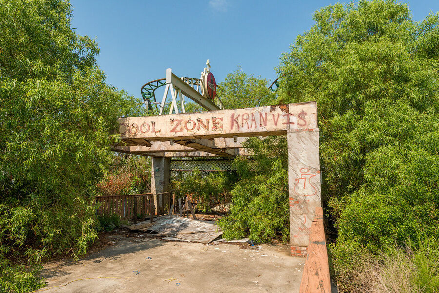Fine art urban exploration photograph of abandoned Six Flags New Orleans roller coaster structure, nature reclaiming concrete and steel