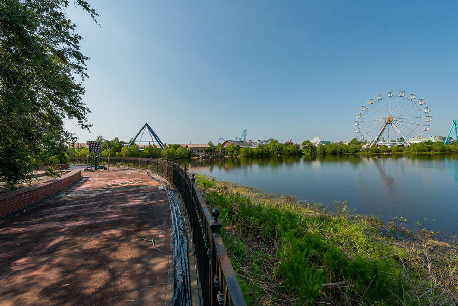 Fine art urban exploration photograph of abandoned Six Flags New Orleans roller coaster structure, nature reclaiming concrete and steel