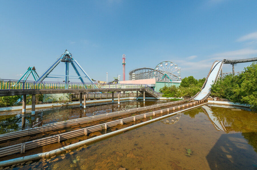 Fine art urban exploration photograph of abandoned Six Flags New Orleans roller coaster structure, nature reclaiming concrete and steel