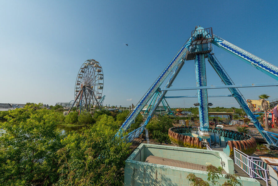 Large format fine art print of the derelict Six Flags New Orleans park at golden hour, rust and vegetation creating an atmosphere of quiet desolation