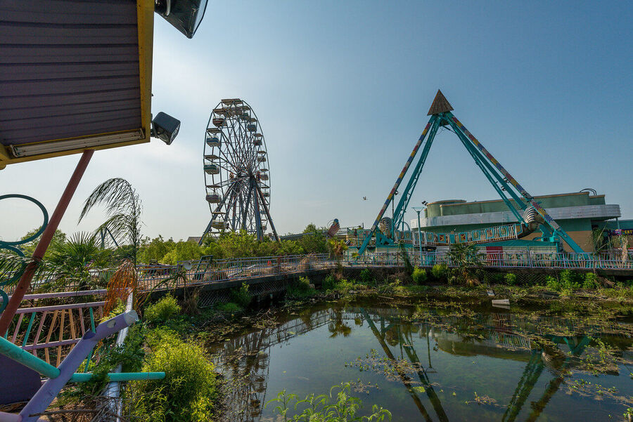 Large format fine art print of the derelict Six Flags New Orleans park at golden hour, rust and vegetation creating an atmosphere of quiet desolation
