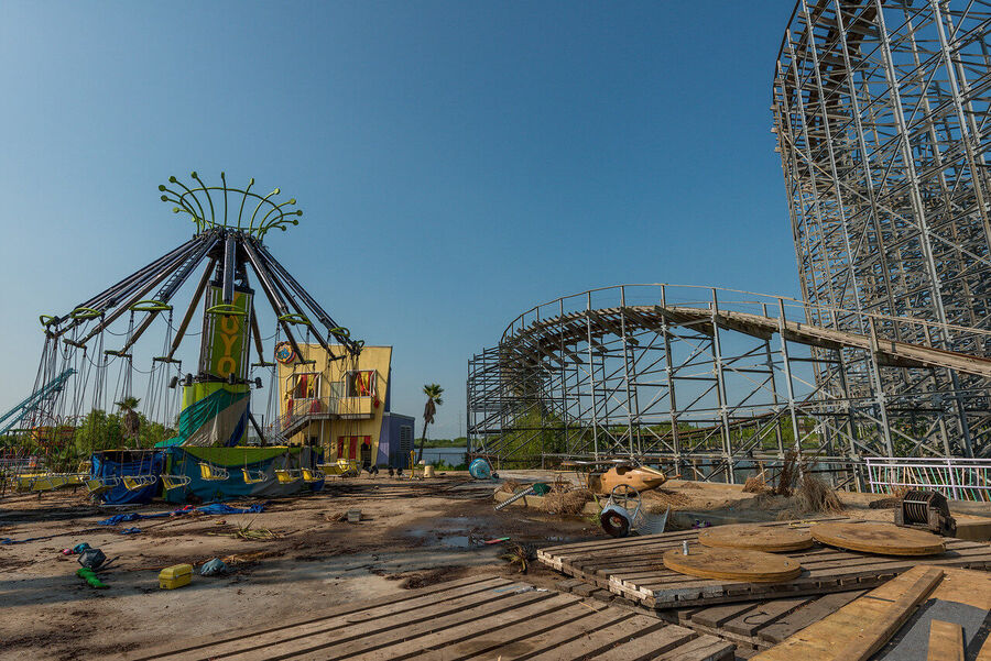 Large format fine art print of the derelict Six Flags New Orleans park at golden hour, rust and vegetation creating an atmosphere of quiet desolation