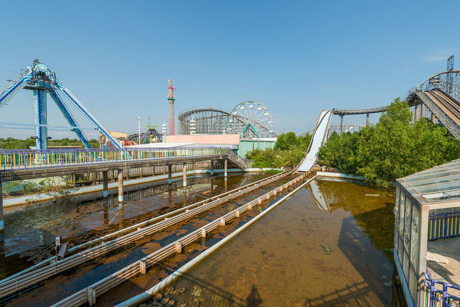 Large format fine art print of the derelict Six Flags New Orleans park at golden hour, rust and vegetation creating an atmosphere of quiet desolation