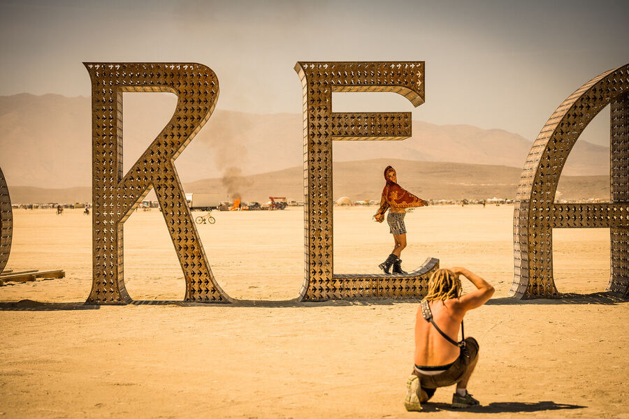 Fine art documentary photograph from Black Rock City, Nevada — the temporary city of 70,000 emerging from the playa dust at dusk