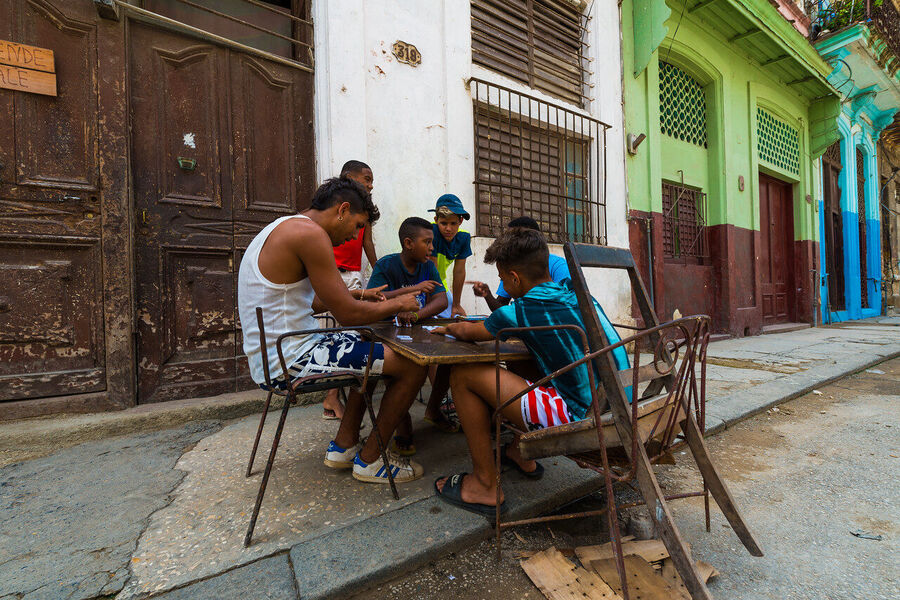 Fine art documentary print of a Havana musician performing in a sun-drenched colonial courtyard, dappled light falling across warm terracotta walls