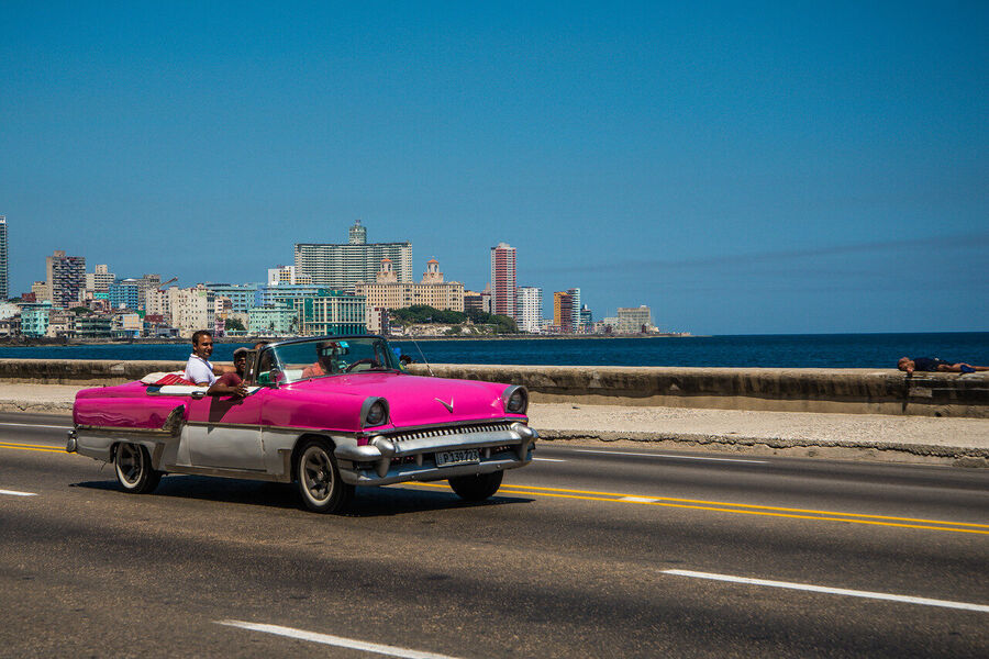 Fine art street photography print of colorful vintage taxis idling along a Havana boulevard, the city's timeless patina on full display