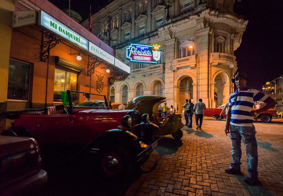Fine art street photography print of colorful vintage taxis idling along a Havana boulevard, the city's timeless patina on full display