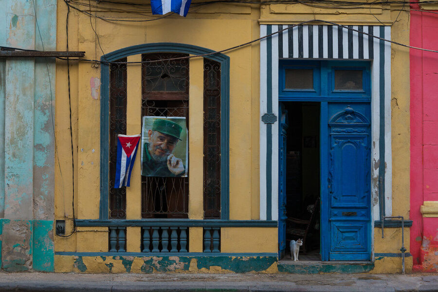 Intimate fine art documentary photograph of a Cuban elder framed in a Havana doorway, warm ambient light revealing every line of a life fully lived