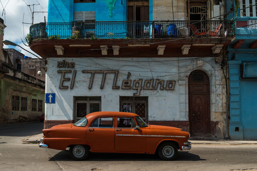 Fine art street photography print of colorful vintage taxis idling along a Havana boulevard, the city's timeless patina on full display