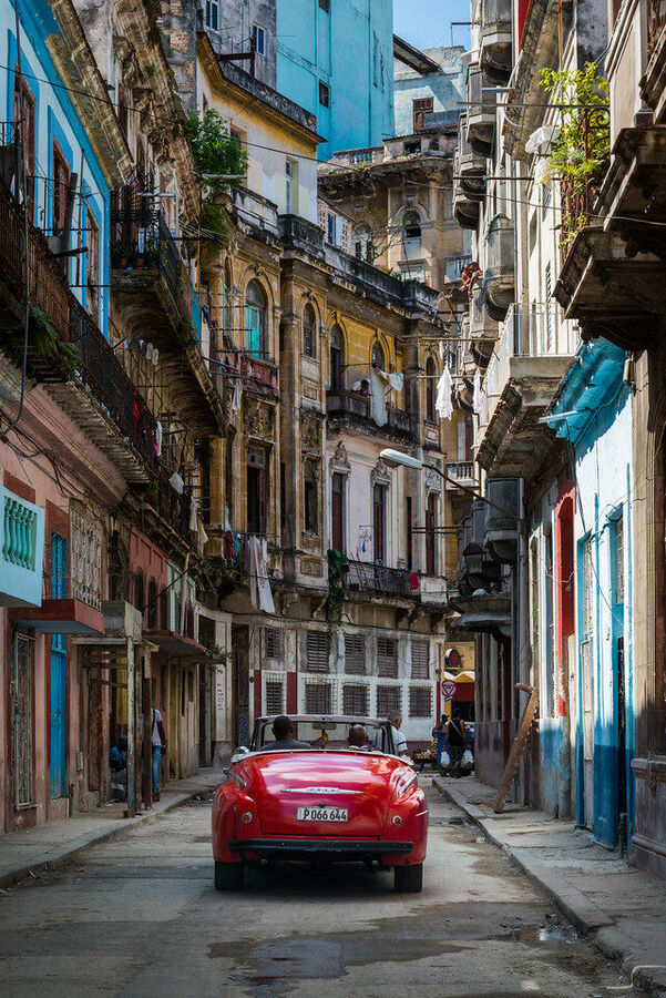 Intimate fine art documentary photograph of a Cuban elder framed in a Havana doorway, warm ambient light revealing every line of a life fully lived