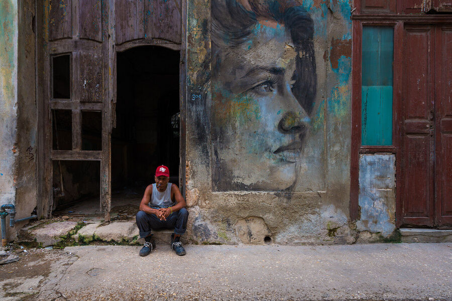 Fine art documentary print of a Havana musician performing in a sun-drenched colonial courtyard, dappled light falling across warm terracotta walls