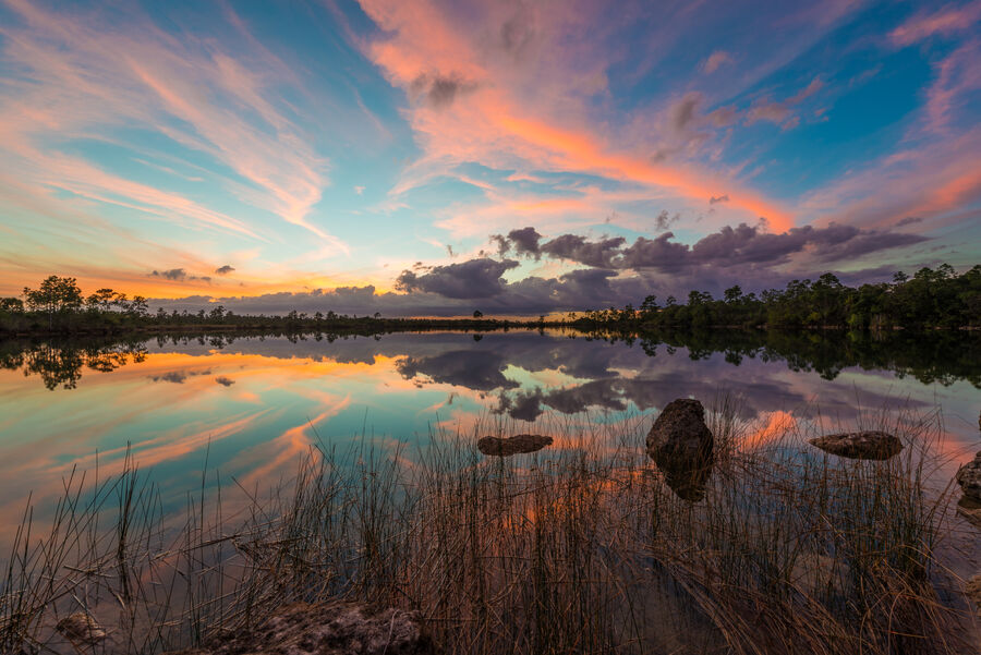 Moody fine art photography print of an Everglades storm cell building over a broad wetland prairie at sunset, sky mirrored in still water