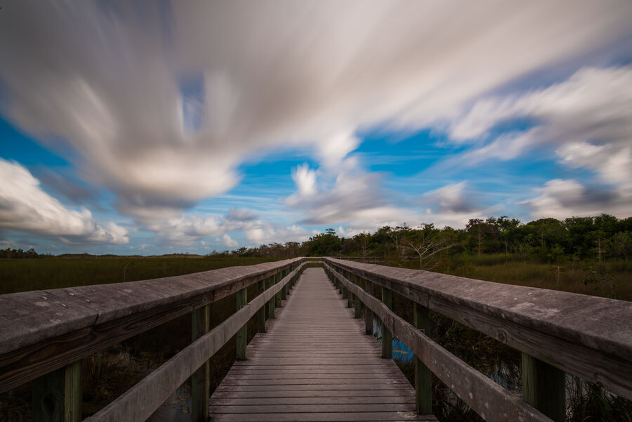 Moody fine art photography print of an Everglades storm cell building over a broad wetland prairie at sunset, sky mirrored in still water
