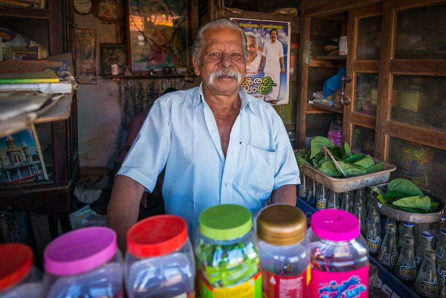 Fine art portrait print of an Indian holy man at dawn, soft ambient light from a temple doorway creating a near-painterly quality