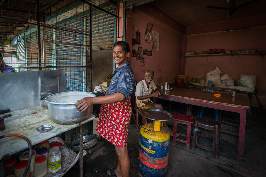 Fine art documentary photograph of a craftsman at work in an Indian market, deep concentration visible in the quality of the available light