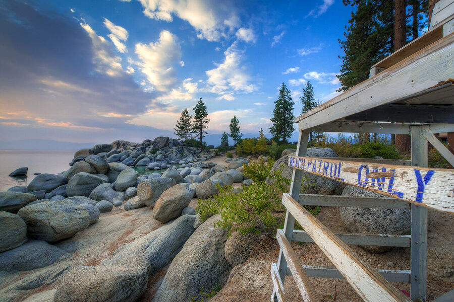 Long exposure fine art photograph of Bonsai Rock in Lake Tahoe at blue hour, smooth wave-washed granite and teal glacial water in perfect stillness