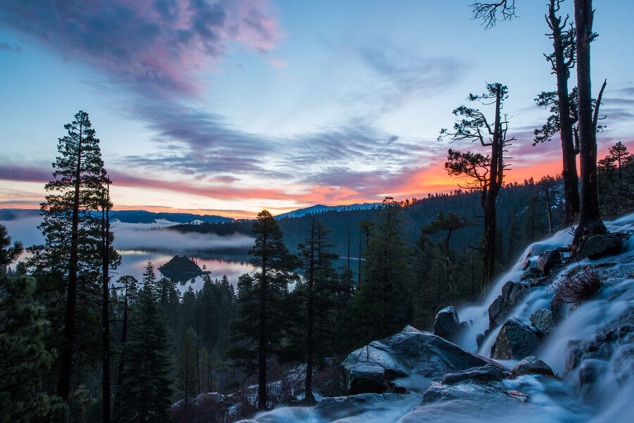 Wide angle fine art landscape print of Lake Tahoe's granite shoreline at golden hour, Sierra Nevada peaks faintly visible through warm atmospheric haze