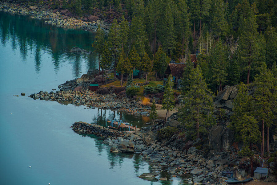 Wide angle fine art landscape print of Lake Tahoe's granite shoreline at golden hour, Sierra Nevada peaks faintly visible through warm atmospheric haze