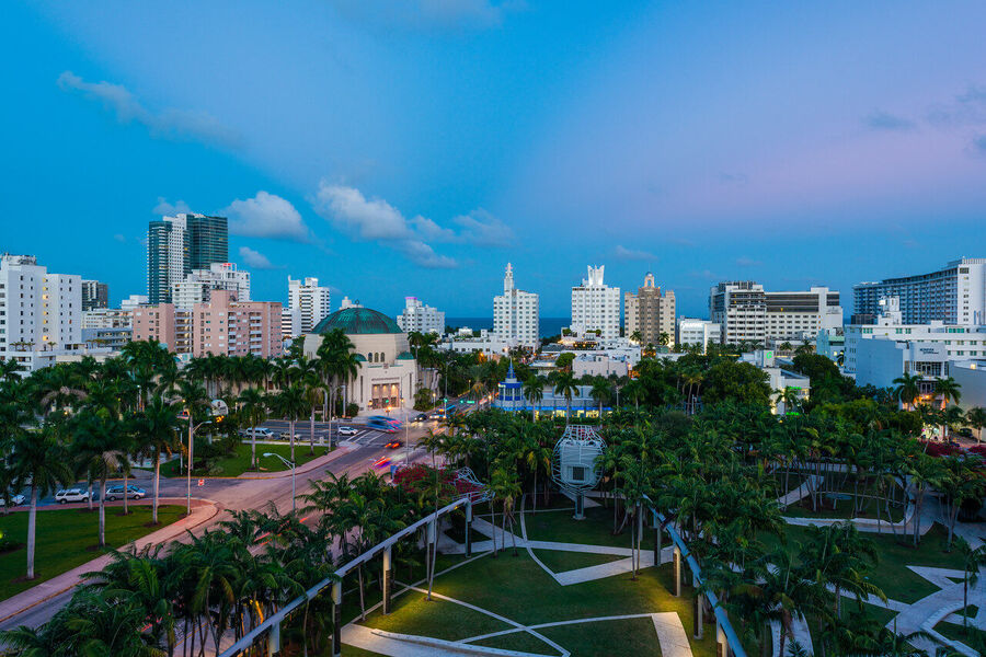 High-contrast fine art photograph of Miami's Art Deco neon signs glowing against an electric blue evening sky