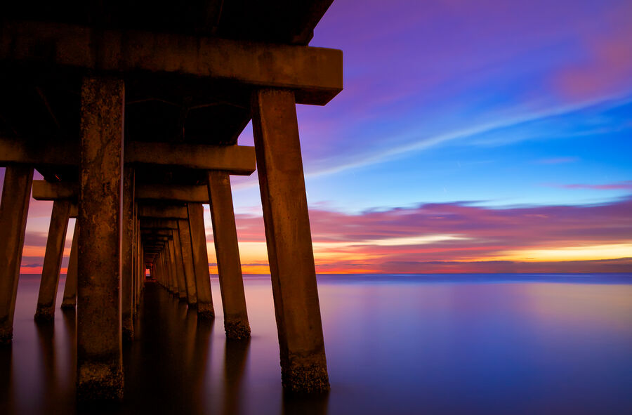 Long exposure fine art photograph of Naples Beach at blue hour, smooth silk-like waves washing the shore under a deep twilight sky