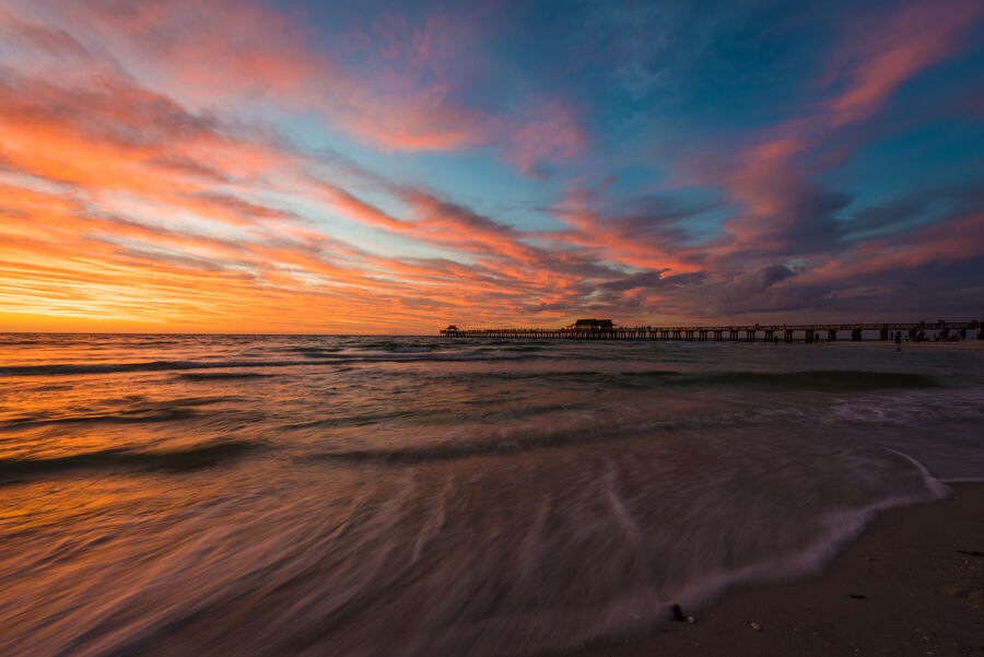 Long exposure fine art photograph of Naples Beach at blue hour, smooth silk-like waves washing the shore under a deep twilight sky